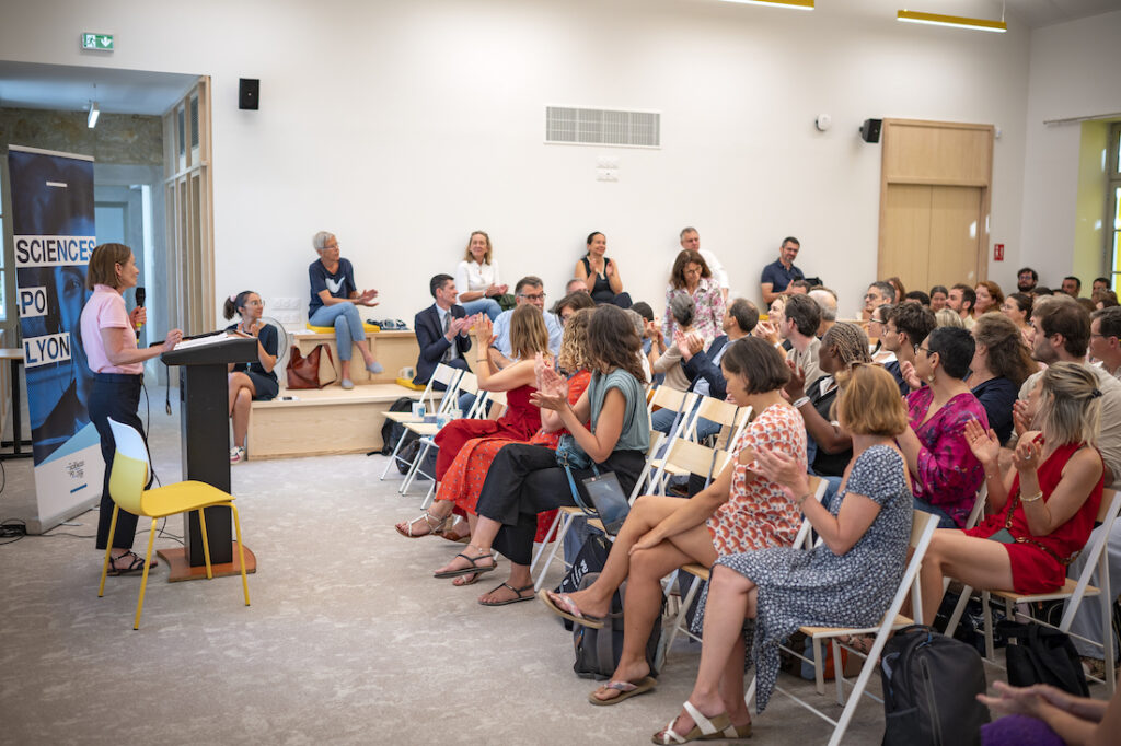 personne sur des chaises qui regarde une femme parler au micro