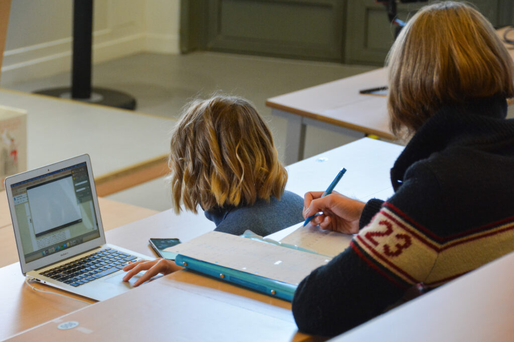 deux personnes de dos qui travaillent sur des tables d'amphithéâtre