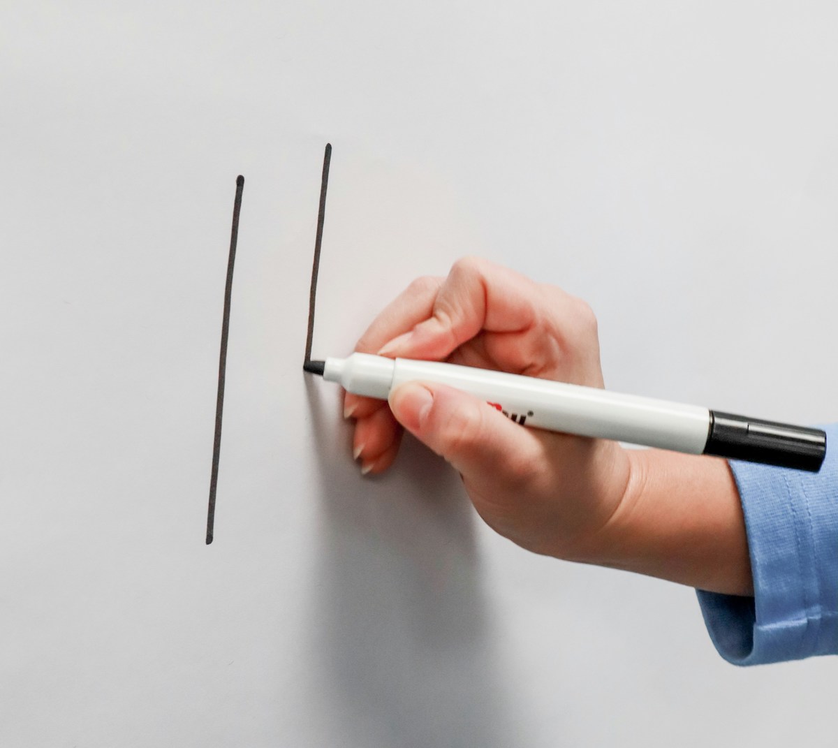 mais qui, à l'aide d'un marqueur noir, dessine deux traits parallèles