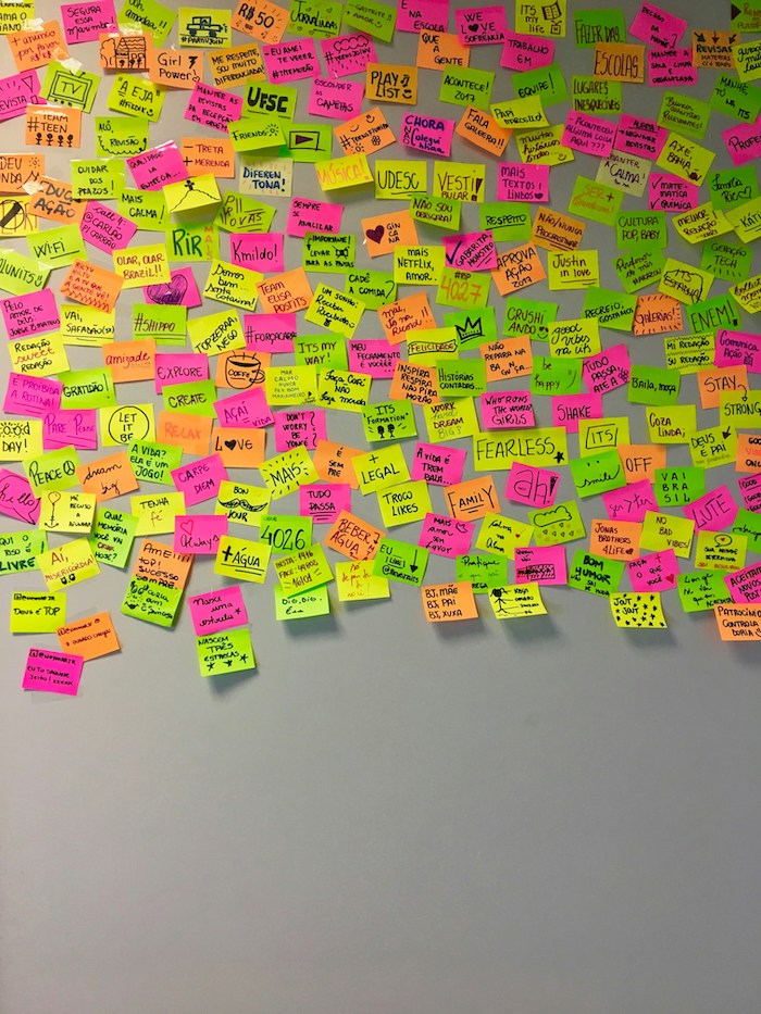 post it affichés sur le 2/3 du haut de la photo avec des dessins et des citations au marqueur, sur un mur gris