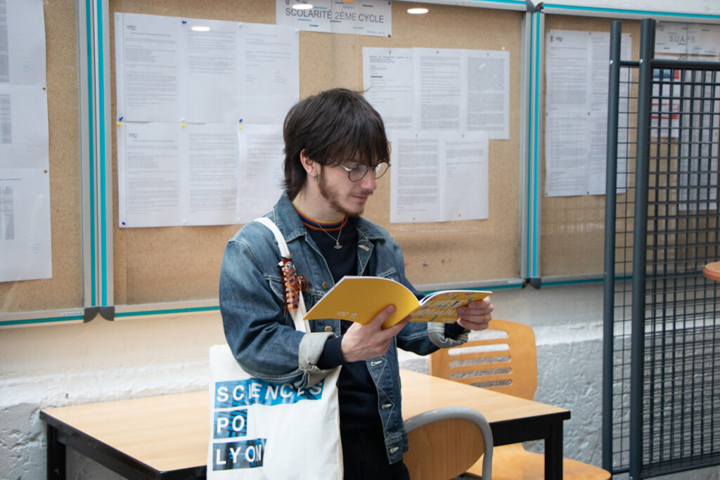 Elève avec un tote bag Sciences Po lyon, qui tient un livre et le lit