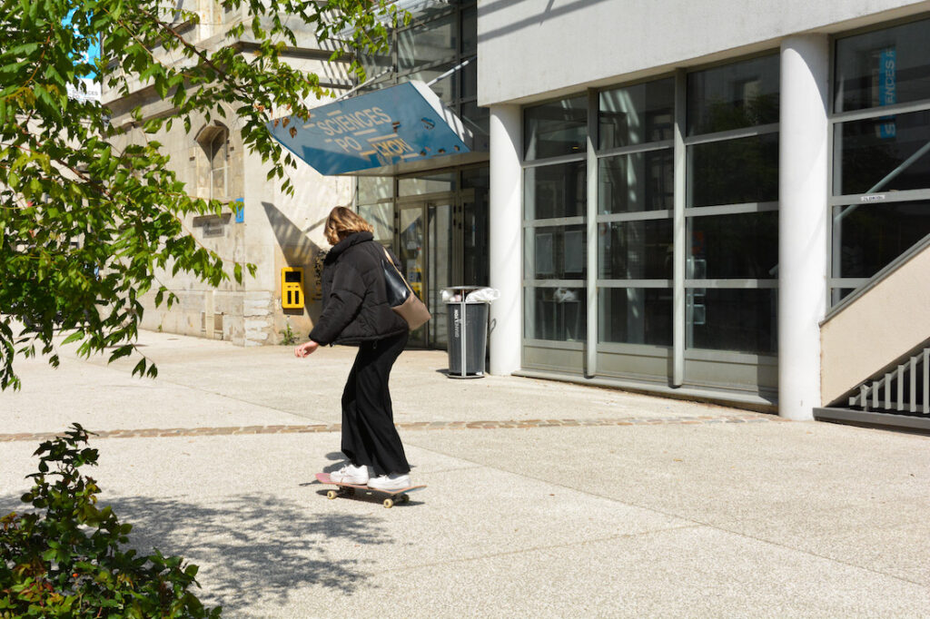 Fille qui fait du skate devant le batiment de sciences po