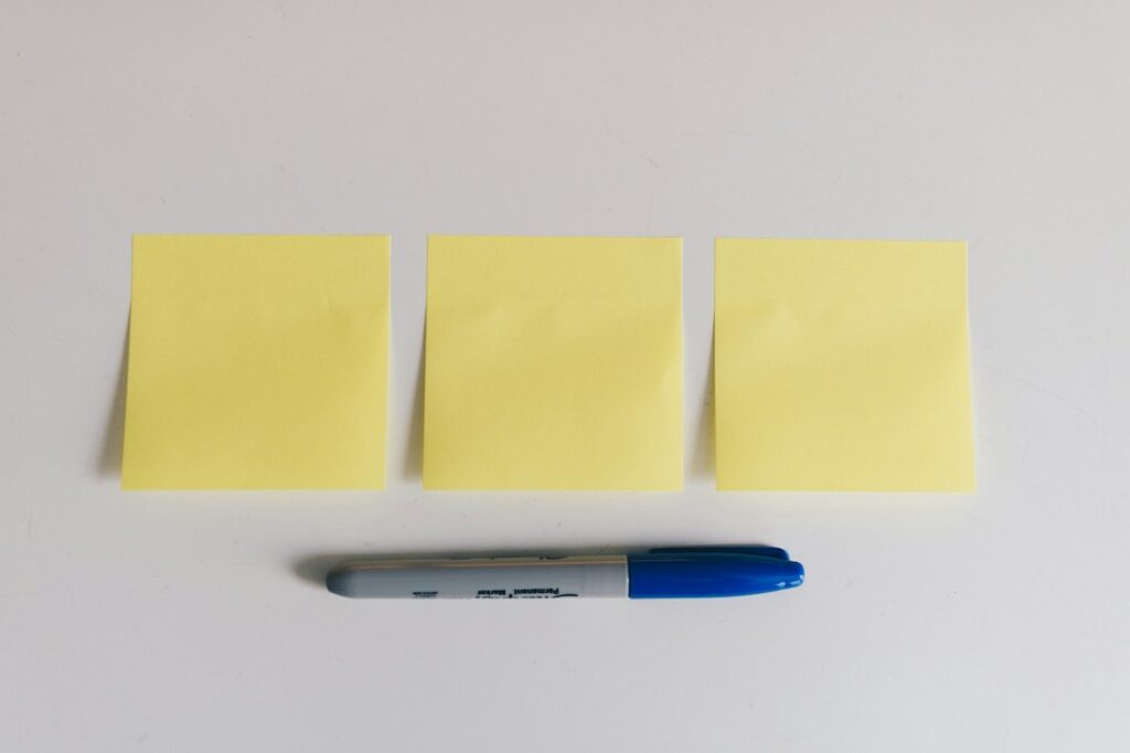 3 post it et un stylo bleu en dessous