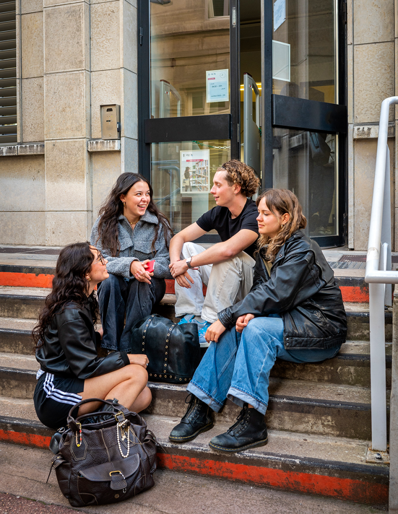 4 élèves assis sur des escaliers qui discutent