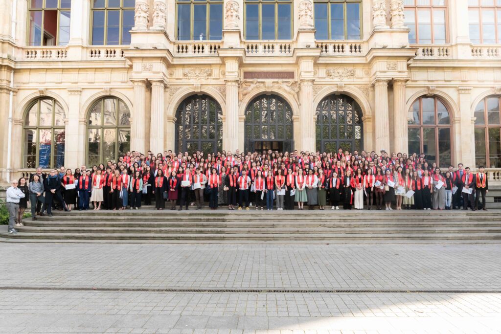 Promotion devant le palais du commerce, avec l'écharpe rouge des diplômés